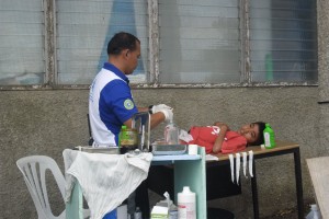 A doctor circumcises a young boy on an office table outside the Palompon general hospital. The building was badly damaged by  the typhoon.